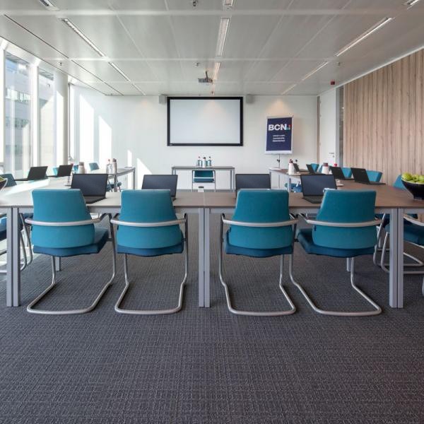 Zaal in Eindhoven met laptops op tafels en blauwe stoelen